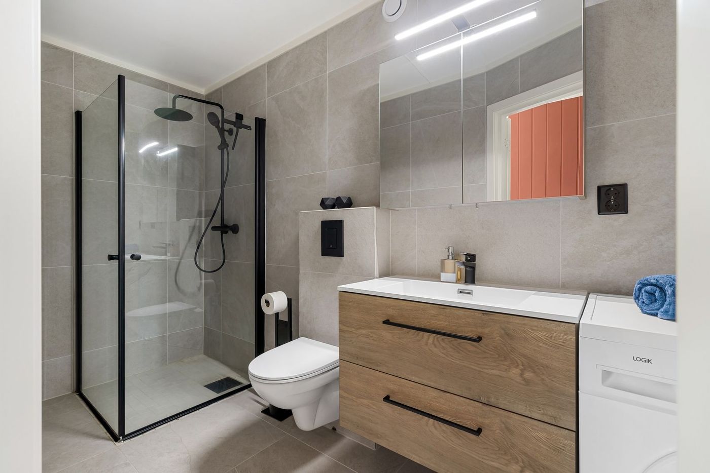 A modern bathroom with a glass shower, wooden vanity and large mirror