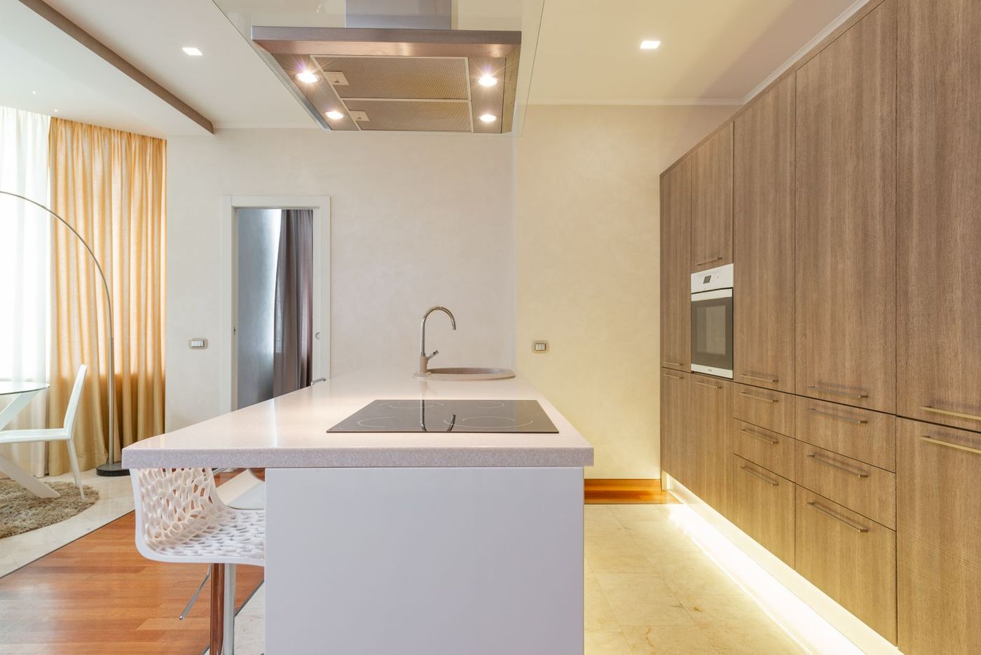 A bright kitchen with wooden cabinets, a white island and a built-in hob